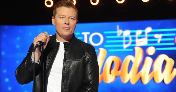 Artysta z wyciągniętym językiem trzyma mikrofon na tle napisu "Jaka to melodia". Czyżby zapowiadał największe zmiany w regulaminie?