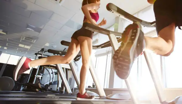 Due persone corrono sui tapis roulant in palestra. Nonostante correre fa venire la cellulite, loro si allenano con determinazione.