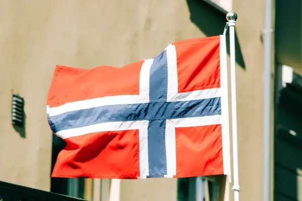 Norweska flaga powiewa na wietrze. Zastanawiasz się, ile zarabia programista w Norwegii?