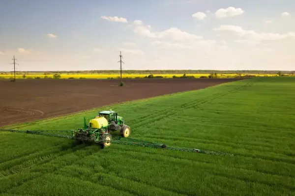 Zielony traktor z opryskiwaczem na polu, przygotowuje się do ochrony upraw przed szkodnikami, jak afalon.