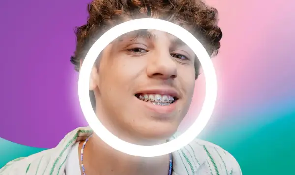 Ragazzo con cera apparecchio, sorride con un cerchio luminoso attorno al viso. Sfondo sfumato viola e verde.