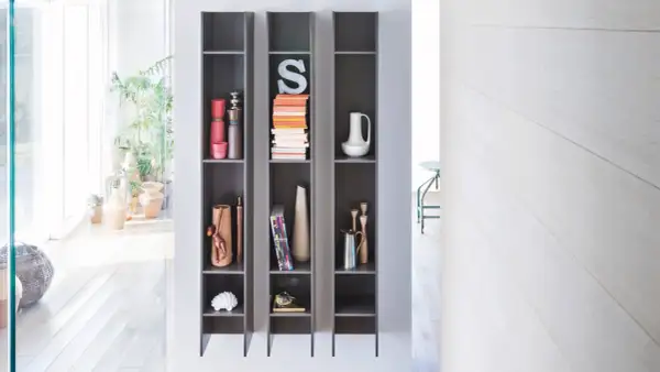 Scaffali grigi con oggetti decorativi, piante e libri, che creano un effetto camino ventilazione naturale.