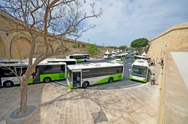 Malta autobusy z lotniska czekają na pasażerów przy zabytkowych murach.