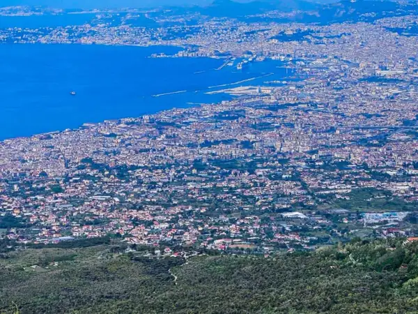 Blick über die weitläufige Stadt Neapel, Italien, mit dem blauen Meer und dem Hafen im Hintergrund.