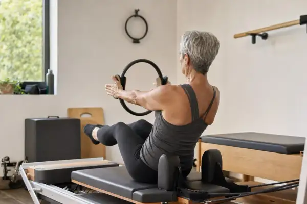 Donna matura con un anello Pilates, impegnata in un allenamento per raddrizzare la schiena a 50 anni.