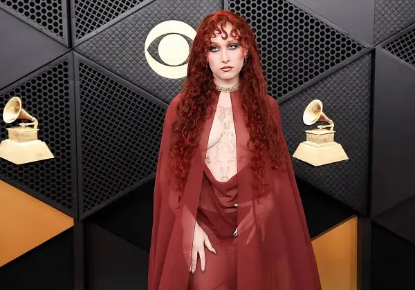 Chappell Roan, con su cabello rojo rizado y un atuendo transparente, posa en la alfombra de los Grammy.