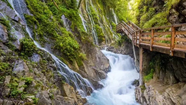 Holzwanderweg führt an rauschenden Wasserfällen vorbei durch die Berchtesgadener Alpen.