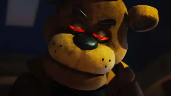 Freddy Fazbear z czerwonymi, świecącymi oczami, wygląda złowrogo w ciemności.