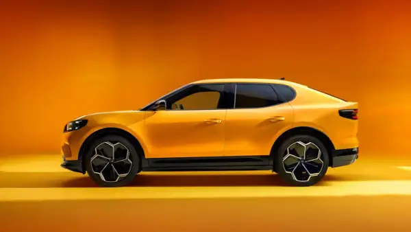 Żółty Ford Capri 2025, sportowy SUV z futurystycznym designem, prezentuje się na tle pomarańczowego gradientu.