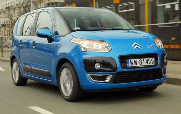 Niebieski Citroen C3 Picasso 2009 jedzie ulicą, mijając tramwaj.