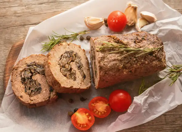 Pyszna rolada z mięsa mielonego z grzybami, podana z pomidorkami i rozmarynem.