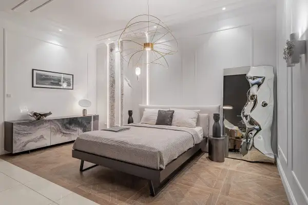 Nowoczesna sypialnia z łóżkiem, marmurową komodą i designerskim lustrem. Inspiracja, jak urządzić sypialnię w eleganckim stylu.