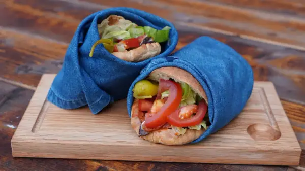 Två kebabrullar med färska grönsaker, inlindade i jeans, serverade på en träbricka. Ett enkelt och gott kebab recept.
