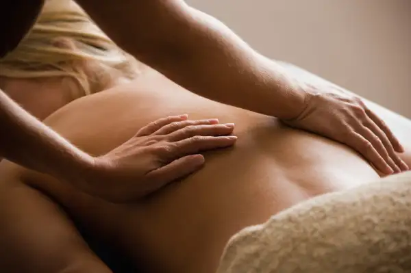 Mains expertes appliquant une technique de massage dos relaxante sur une peau dorée. Douceur et détente assurées.