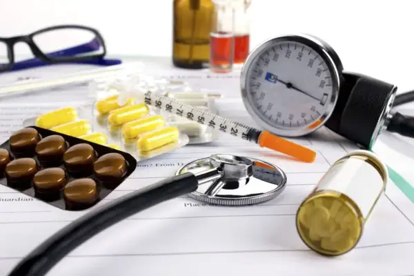 Leki na nadciśnienie: tabletki, strzykawka, ciśnieniomierz i stetoskop na dokumentach medycznych.