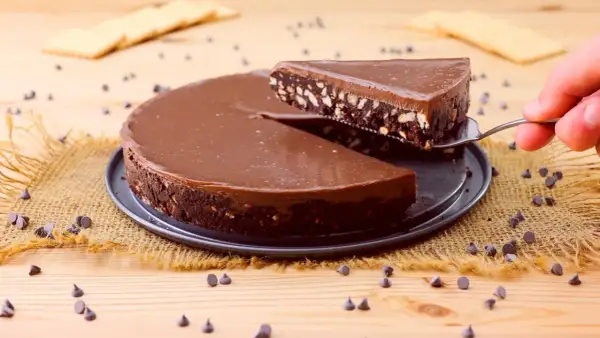 Torta al cioccolato con biscotti, un'idea per dolci velocissimi senza cottura. Una fetta viene sollevata con una paletta.