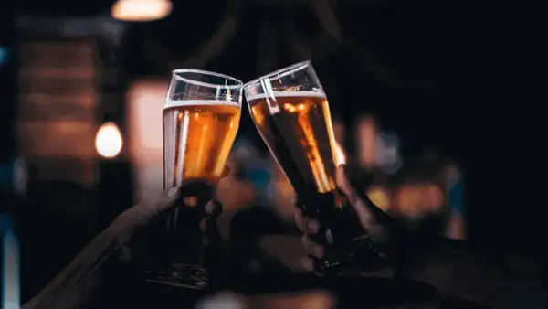 Due mani brindano con due bicchieri di birra dorata, un gesto che nasconde un'intolleranza alla birra.