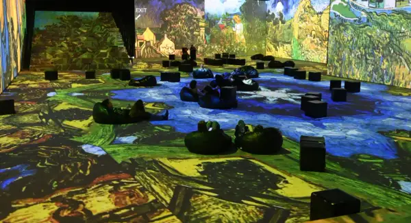 Wystawa Van Gogh w Krakowie. Widzowie odpoczywają na pufach, otoczeni projekcjami dzieł mistrza.