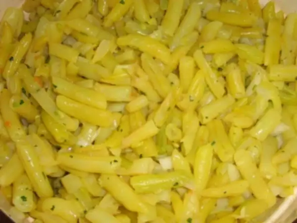 Nahaufnahme von gekochten gelben Bohnen, gewürzt mit Kräutern und Zwiebeln. Ein leckeres Gericht mit gelben Bohnen.