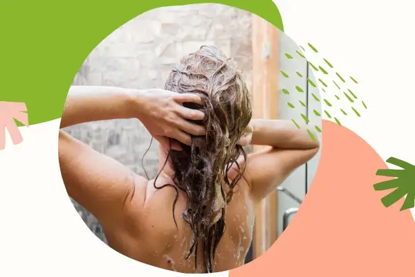 Kobieta masuje mokre włosy pod prysznicem, stosując naturalny peeling do skóry głowy.