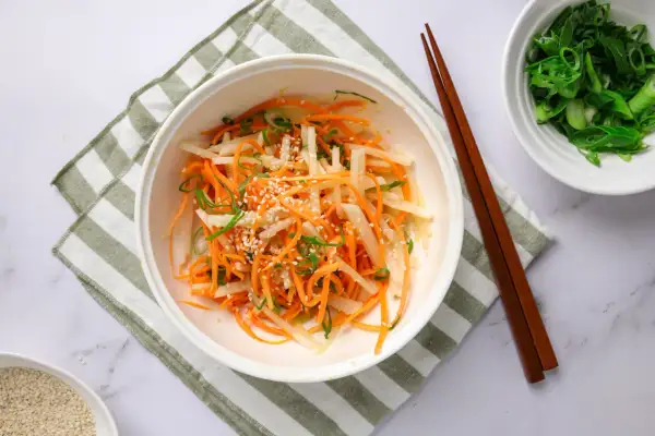 En fräsch sallad med strimlad daikon, morot och salladslök, toppad med sesamfrön. Ett enkelt daikon recept.