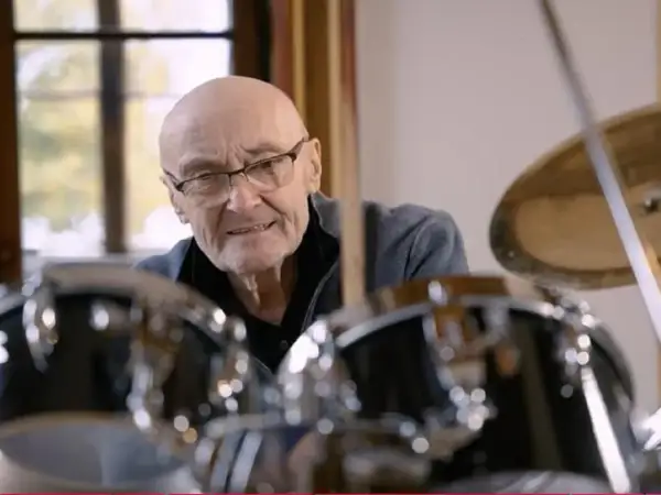 Phil Collins, legenda perkusji, siedzi przy zestawie bębnów, gotów do gry.