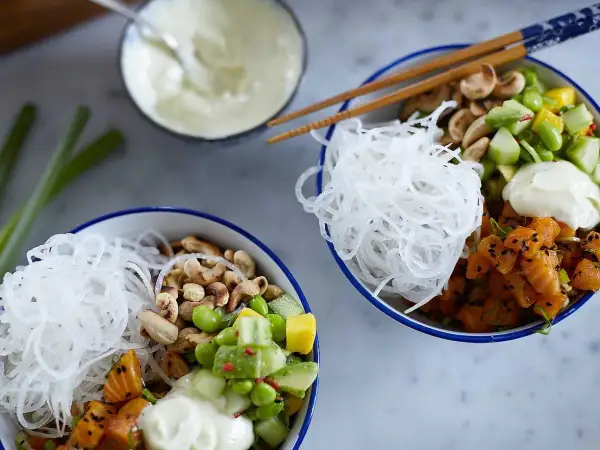 Två färgglada pokebowls med lax, grönsaker, nötter och risnudlar. Ett perfekt pokebowl recept för en hälsosam lunch.