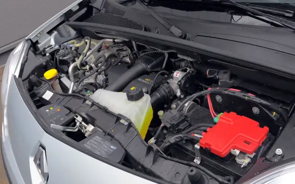 Silnik Renault Kangoo 2 z widocznym zbiorniczkiem płynu chłodniczego, akumulatorem i czerwonymi osłonami.