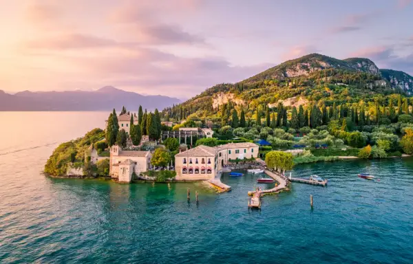 Un'isola incantevole sul gardasee westufer, con ville storiche, cipressi e ulivi, bagnata da acque turchesi al tramonto.