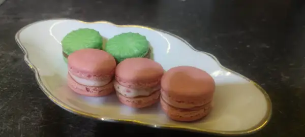 Przepis na makaroniki Ani Gotuje: różowe i zielone makaroniki z kremowym nadzieniem na ozdobnej porcelanowej paterze.