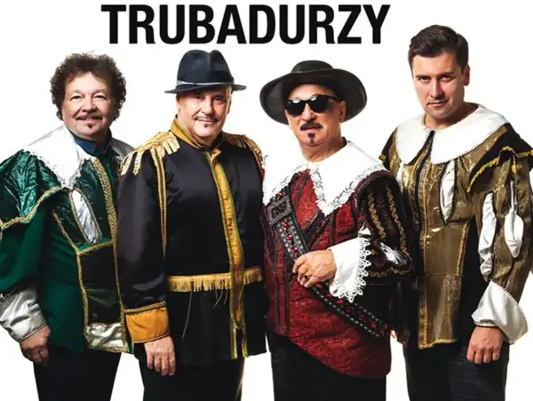 Czterech mężczyzn w barwnych strojach, przypominających stroje z epoki, pozuje do zdjęcia. Nad nimi widnieje napis "TRUBADURZY".