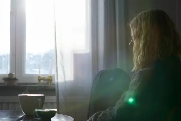 En person sitter ensam vid ett fönster med en kopp kaffe. Kanske en stund av reflektion kring att sluta dricka alkohol och hantera depression.