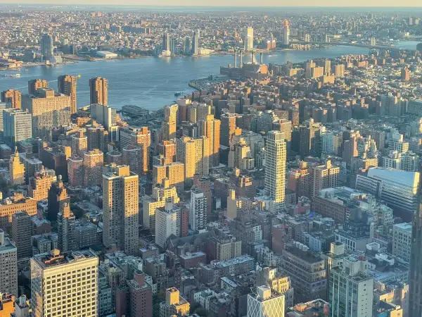 Widok z lotu ptaka na Manhattan i Brooklyn o zachodzie słońca. Rzeka Hudson rozdziela dwa miasta, a światła miasta zaczynają migotać.
