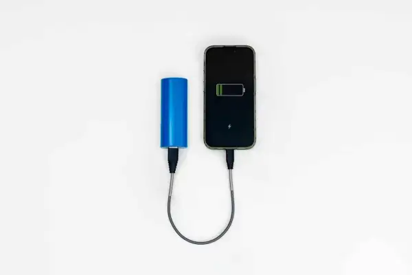 Niebieski power bank ładuje smartfon. Idealny, gdy zastanawiasz się, jaki power bank do samolotu zabrać, by mieć zawsze naładowany telefon.