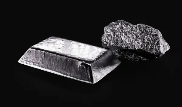 Sztabka i bryła platyny, najdroższego metalu na świecie, lśnią na czarnym tle.