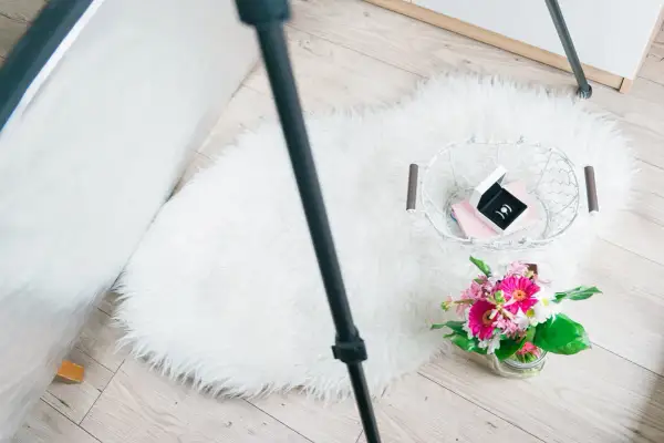 Zdjęcia flat lay: białe futrzane dywaniki, koszyk z biżuterią i bukiet kwiatów.