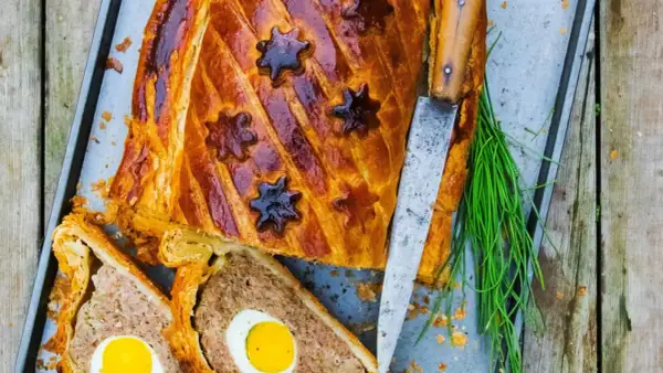 Pâté de Pâques doré, décoré d'étoiles, avec des œufs entiers au cœur. Une recette festive prête à être dégustée.