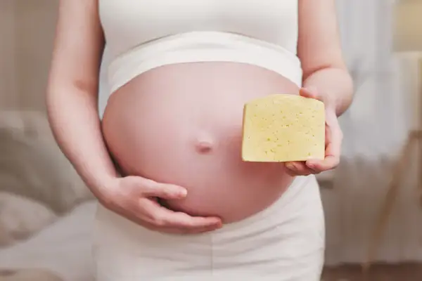 Ciężarna kobieta trzyma kawałek sera. Czy to camembert w ciąży?