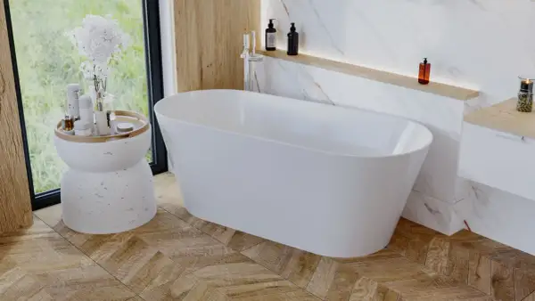 Elegancka wolnostojąca wanna w łazience z drewnianą podłogą ułożoną we wzór jodełki. Obok wanny stoi stolik z kosmetykami i kwiatami.