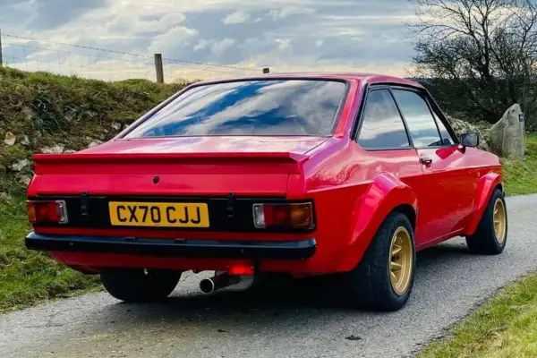 Röd Ford Escort MK2 med breddade skärmar och gul registreringsskylt.