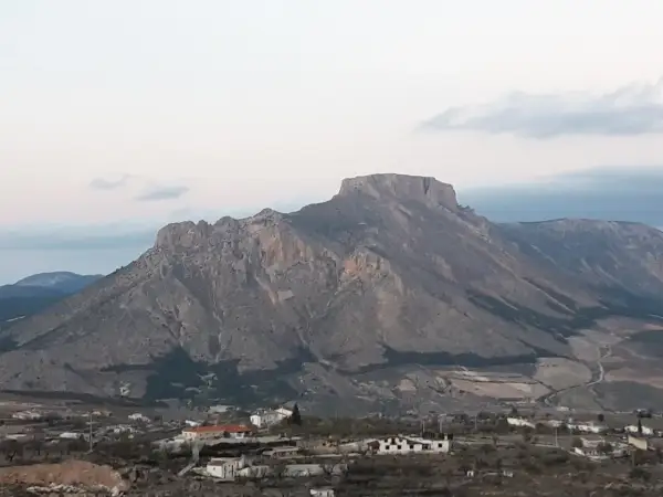 Majestuosa sierra de la Muela con sus picos rocosos y un pequeño pueblo a sus pies.