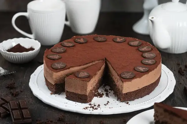 Eine köstliche Schoko Torte, bestäubt mit Kakao und verziert mit Schokoladensternen und Rentieren. Ein Stück ist bereits angeschnitten.