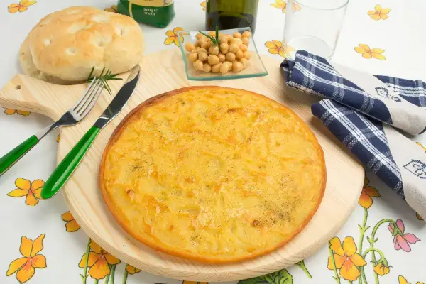Farinata di ceci in padella, dorata e profumata, pronta per essere gustata con pane fresco e un rametto di rosmarino.