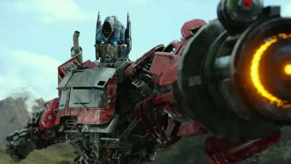 Optimus Prime, przywódca Autobotów, z niebieskimi oczami i płonącą bronią, gotowy do walki.