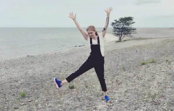 Glad tjej med armarna uppe på en stenig strand på Gotland i Sverige.