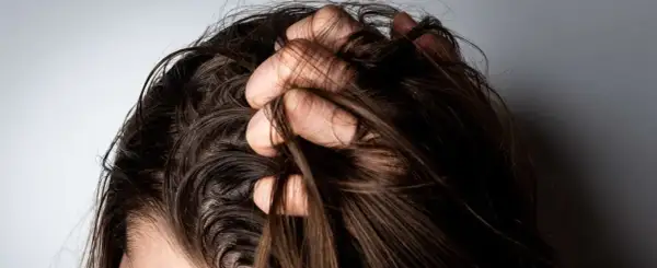 Mano revolviendo cabello oscuro. ¿Es mejor teñirse con el pelo sucio o limpio?