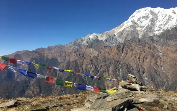Vackra böneflaggor fladdrar i vinden under en snöklädd bergstopp. En oförglömlig upplevelse av att vandra i Nepal.