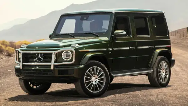 Un imponente Mercedes-Benz verde oscuro, el mejor Mercedes del mundo, se detiene en un camino polvoriento con montañas al fondo.