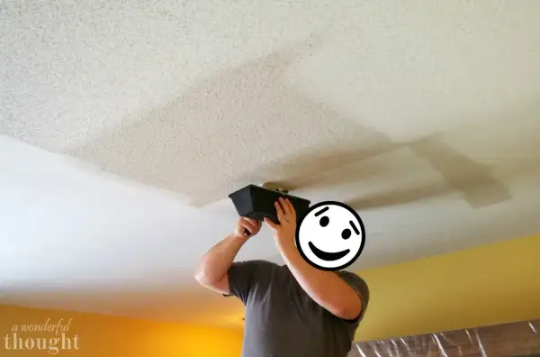 Person applying joint compound to a ceiling, a step in removing popcorn ceiling texture.