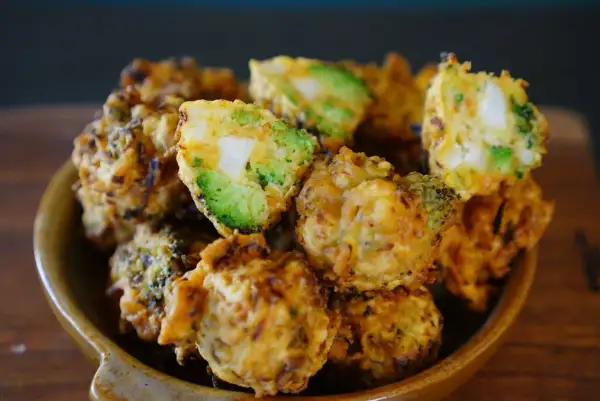 Beignets de légumes croustillants, un délice doré avec des morceaux de brocoli et de pomme de terre bien visibles.